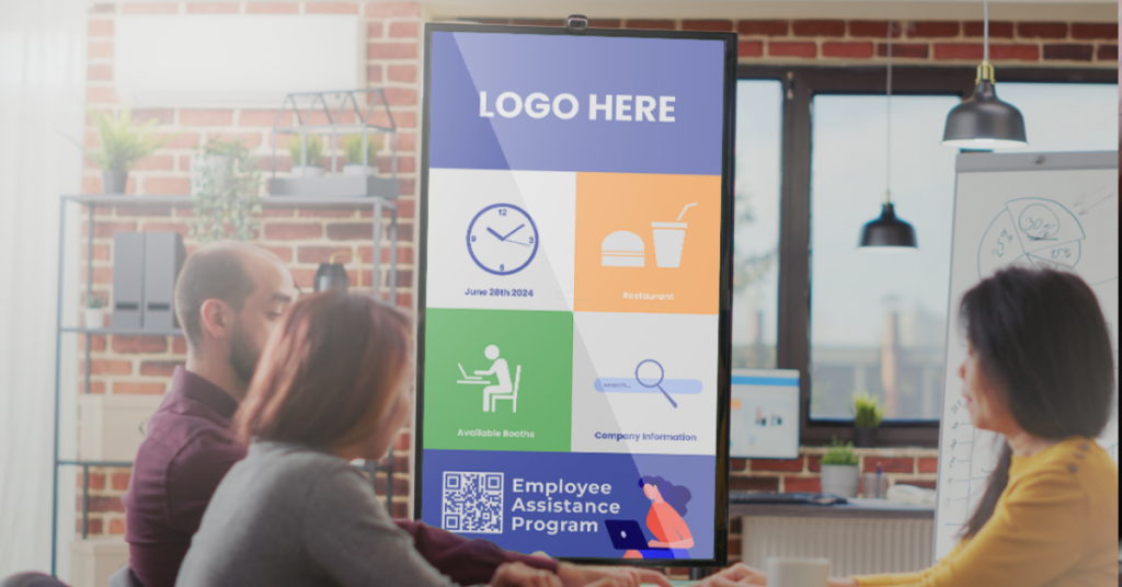 Three employees looking at a digital signage screen