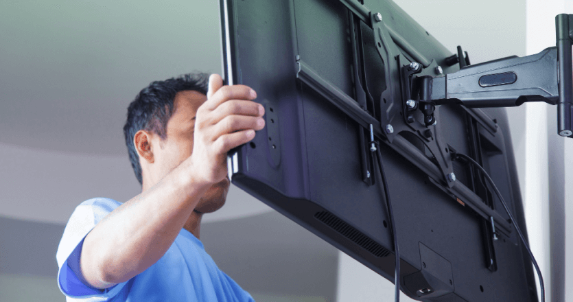 A man setting up a smart TV on a wall mount