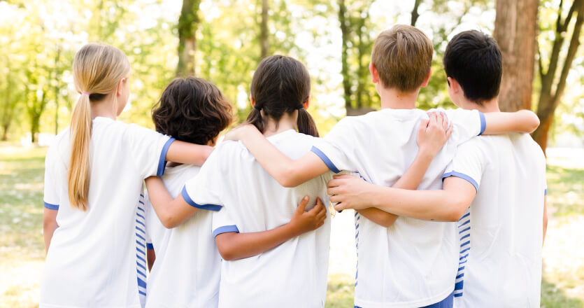 5 kids hugging each other in a forest