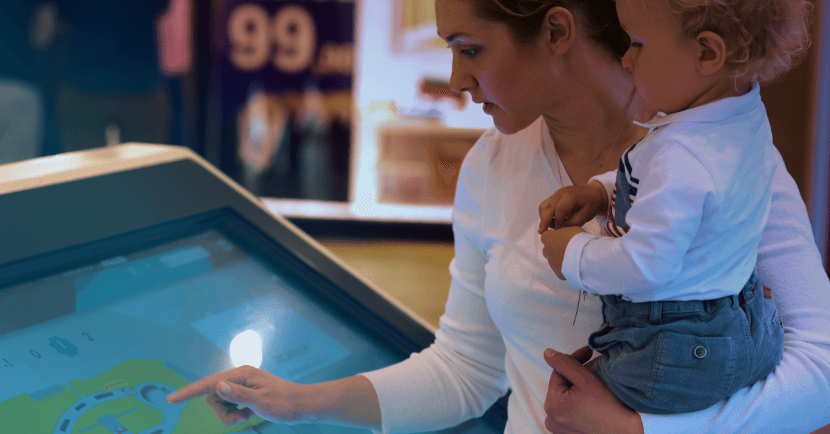 A mother with her child are using an interactive touch screen