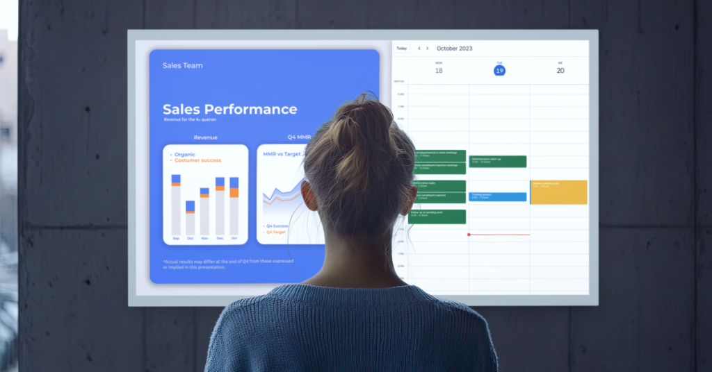 A woman looking at a digital signage screen with sales performance metrics and a calendar